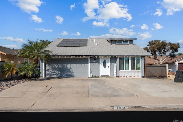 view of front of home featuring driveway, roof with shingles, an attached garage, and roof mounted solar panels