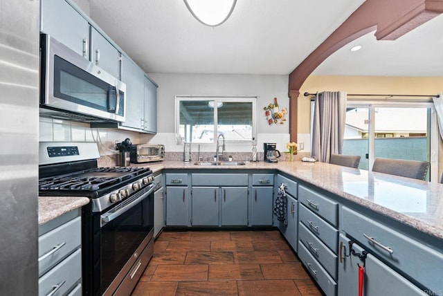 kitchen featuring stainless steel appliances, a healthy amount of sunlight, a sink, and gray cabinetry