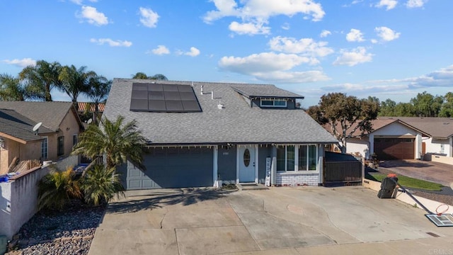 view of front of house featuring a garage, solar panels, roof with shingles, and driveway