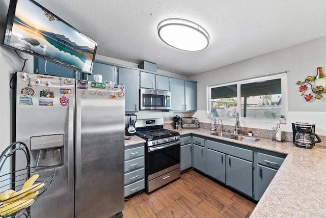 kitchen featuring dark wood-style flooring, light countertops, gray cabinetry, appliances with stainless steel finishes, and a sink