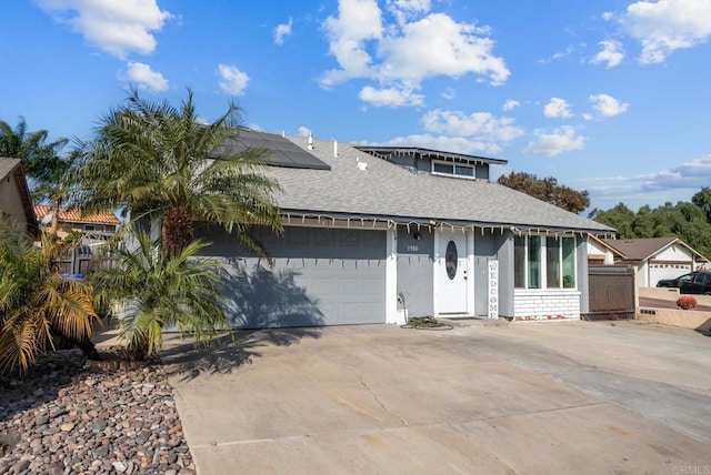 view of front of home with a shingled roof, roof mounted solar panels, driveway, and an attached garage