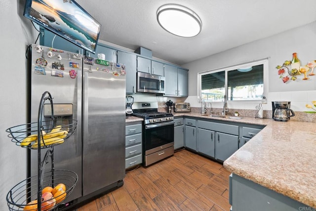 kitchen with dark wood finished floors, light countertops, gray cabinetry, appliances with stainless steel finishes, and a sink