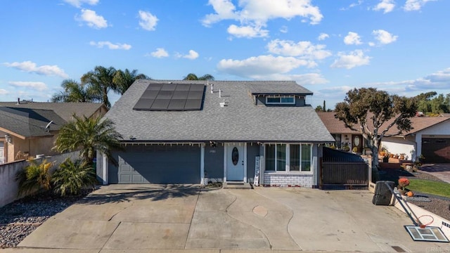 view of front of home featuring solar panels, roof with shingles, an attached garage, and driveway