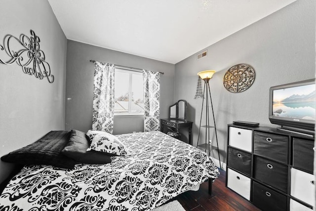 bedroom featuring dark wood-style floors, lofted ceiling, visible vents, and baseboards