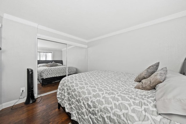 bedroom featuring a closet, crown molding, baseboards, and wood finished floors