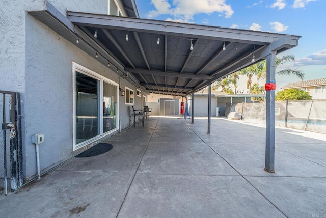 view of patio featuring an outbuilding, fence, and a storage unit