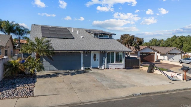 view of front facade with a shingled roof, roof mounted solar panels, brick siding, and a garage