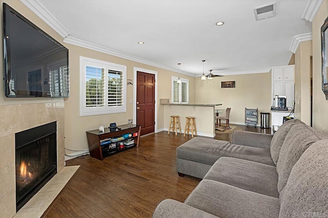 living area featuring visible vents, wood finished floors, crown molding, a fireplace, and recessed lighting