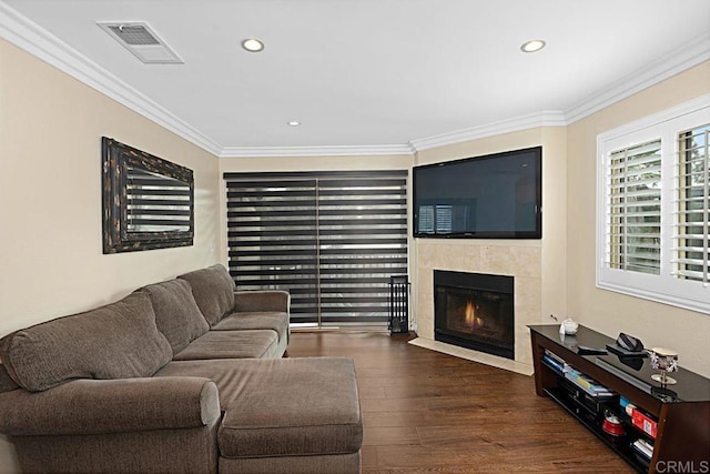 living room featuring visible vents, crown molding, a fireplace, and wood finished floors