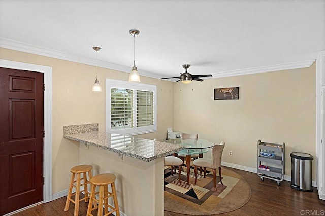 kitchen with dark wood-type flooring, a breakfast bar, and ornamental molding