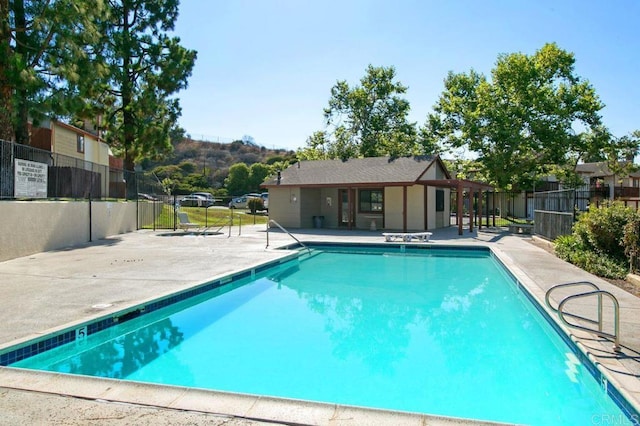 community pool with a patio area and fence