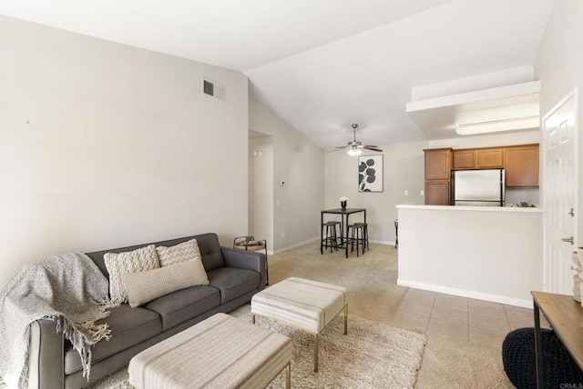 living room with light tile patterned floors, visible vents, vaulted ceiling, ceiling fan, and baseboards