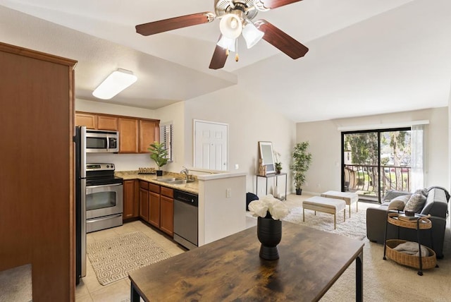 kitchen with brown cabinets, open floor plan, stainless steel appliances, a sink, and light tile patterned flooring