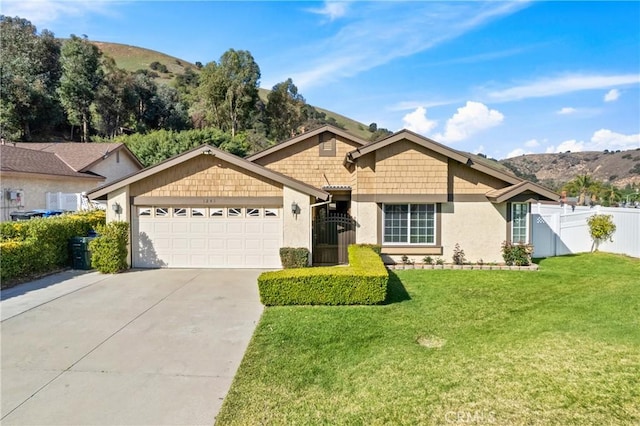 single story home featuring a garage, a front yard, fence, and a mountain view