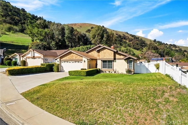 ranch-style home with driveway, a garage, fence, a mountain view, and a front yard