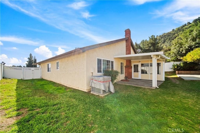 back of house with a yard, a fenced backyard, a patio, and stucco siding