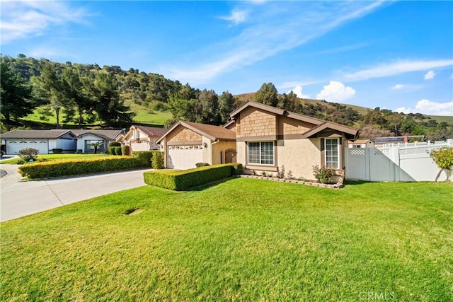 ranch-style home featuring driveway, a gate, fence, and a front lawn