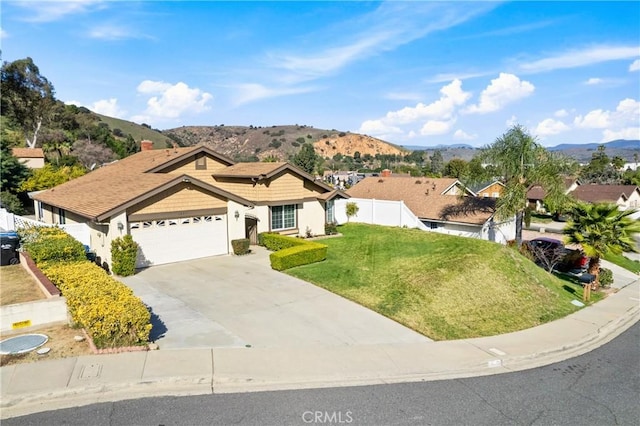 ranch-style house featuring a garage, concrete driveway, fence, a mountain view, and a front lawn