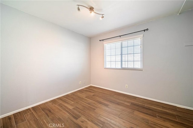 unfurnished room featuring baseboards and wood finished floors