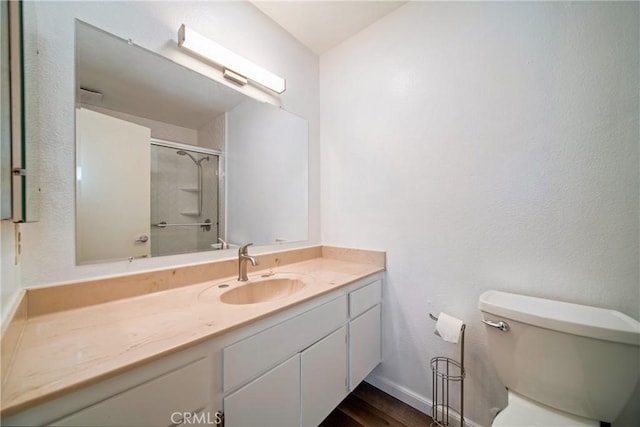 full bath featuring baseboards, toilet, wood finished floors, an enclosed shower, and vanity