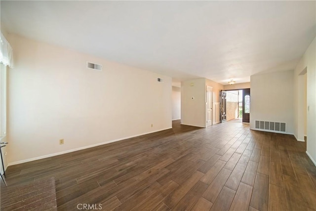 unfurnished living room featuring baseboards, visible vents, and dark wood finished floors