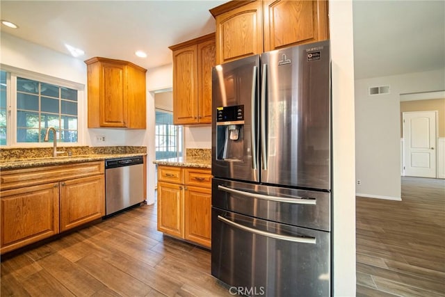 kitchen with visible vents, dark wood-style floors, appliances with stainless steel finishes, light stone counters, and a sink