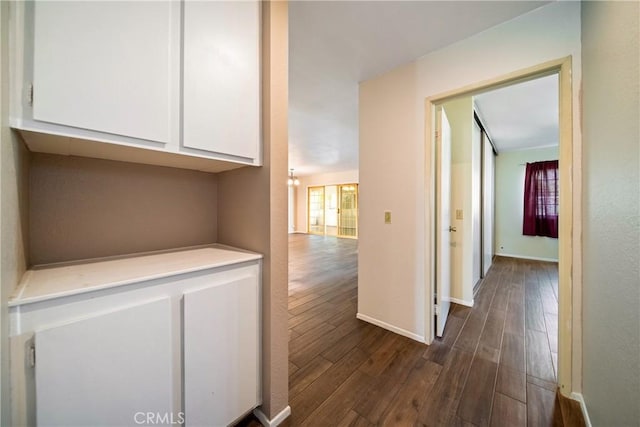 hallway with dark wood-style floors and baseboards