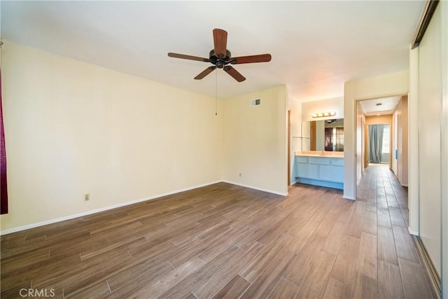 unfurnished living room featuring a ceiling fan, visible vents, baseboards, and wood finished floors