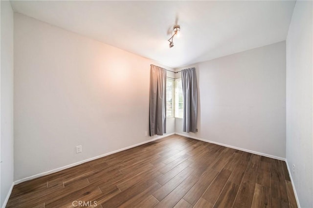 unfurnished room featuring dark wood finished floors and baseboards