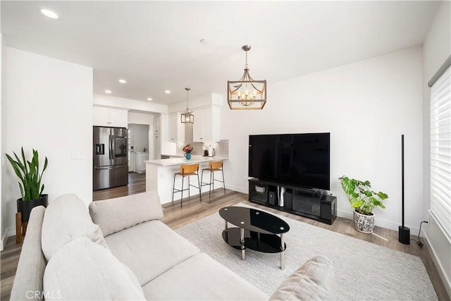 living area featuring a chandelier, light wood-type flooring, baseboards, and recessed lighting