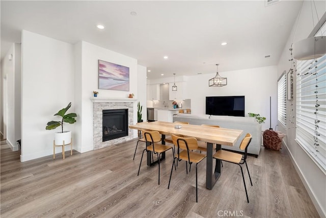 dining room featuring recessed lighting, a fireplace, and light wood finished floors