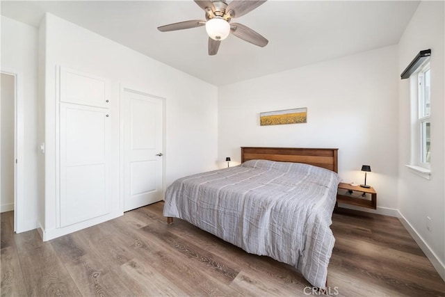 bedroom with a ceiling fan, baseboards, and wood finished floors