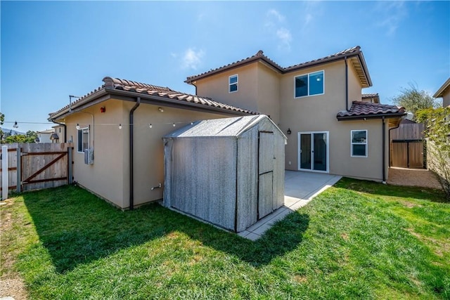 rear view of property with a gate, a lawn, and a tiled roof