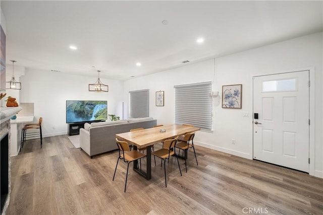 dining area featuring visible vents, baseboards, light wood-style floors, a fireplace, and recessed lighting