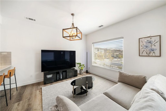 living room featuring a chandelier, wood finished floors, visible vents, and baseboards