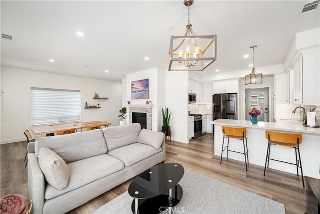 living area featuring light wood-style flooring, a glass covered fireplace, visible vents, and recessed lighting