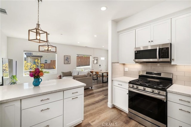 kitchen featuring stainless steel appliances, light wood-type flooring, light countertops, and tasteful backsplash