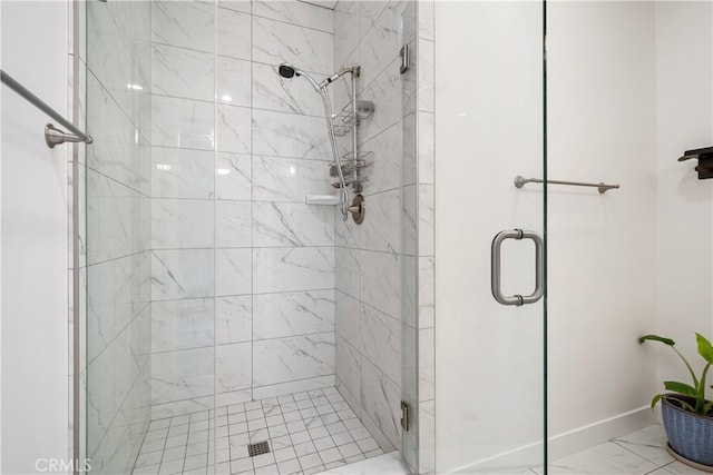 bathroom with marble finish floor, a shower stall, and baseboards