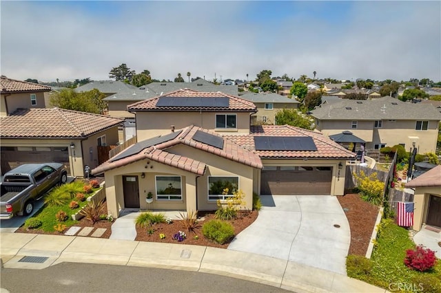 mediterranean / spanish home with a garage, a residential view, solar panels, and stucco siding