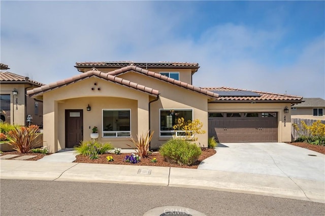 mediterranean / spanish-style home featuring concrete driveway, solar panels, a tiled roof, an attached garage, and stucco siding