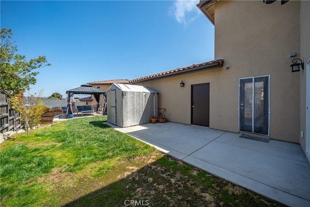 rear view of property featuring a storage shed, a fenced backyard, a gazebo, a patio area, and stucco siding