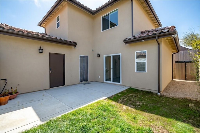 back of property featuring a patio, a yard, a tile roof, and stucco siding