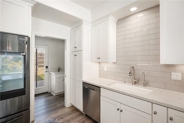 kitchen with refrigerator, wood finished floors, a sink, stainless steel dishwasher, and backsplash