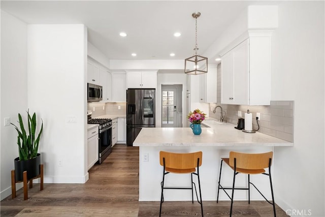 kitchen with a peninsula, appliances with stainless steel finishes, a sink, and light countertops