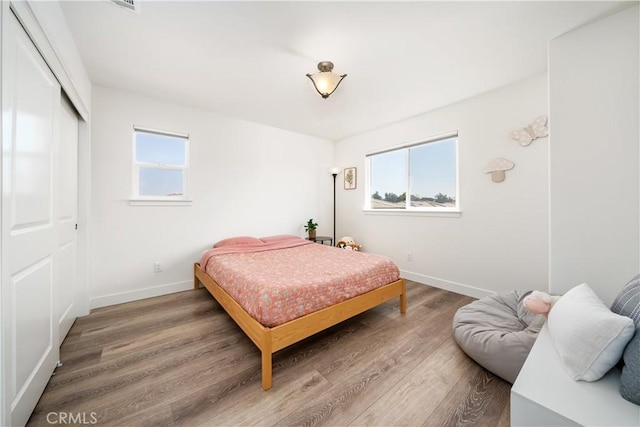 bedroom featuring a closet, wood finished floors, and baseboards