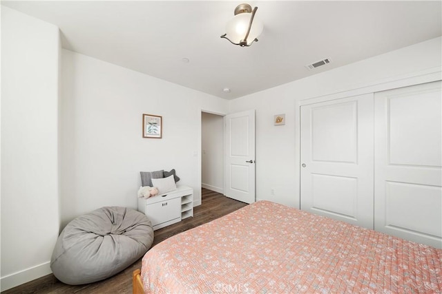 bedroom with dark wood-style floors, a closet, visible vents, and baseboards