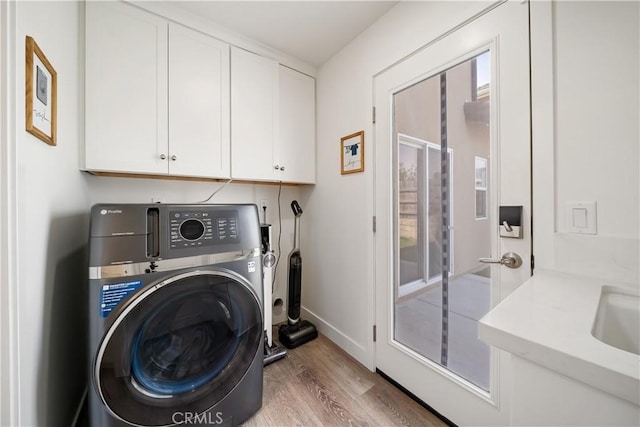 washroom with cabinet space, baseboards, washer / clothes dryer, wood finished floors, and a sink