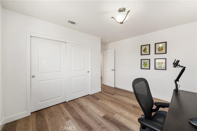 office area featuring baseboards, visible vents, and wood finished floors