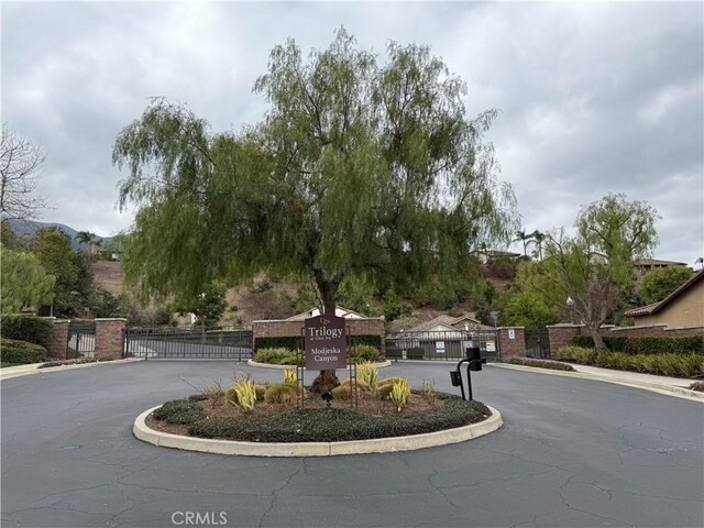 8853 Hollyhock Ct, Corona, CA 92883 - view of asphalt street featuring a gate, curbs, and a gated entry