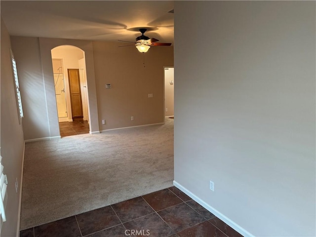 8853 Hollyhock Ct, Corona, CA 92883 - spare room with dark colored carpet, arched walkways, ceiling fan, baseboards, and dark tile patterned flooring